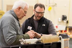 men using a lathe with block of wood