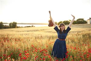 woman holding ukulele in flower field