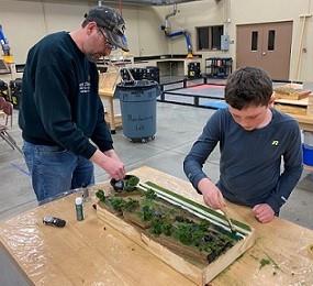 father and son building model train set