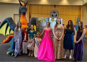 group of kids posing in fairytale outfits and a dragon