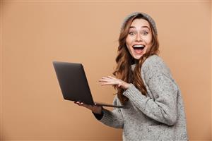 woman with excited expression holding laptop