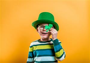 Boy dressed in leprechaun hat holding a four leaf clover