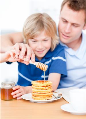 dad and son dripping honey onto waffles