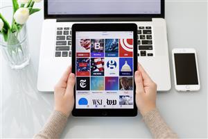 Person holding tablet over a laptop keyboard