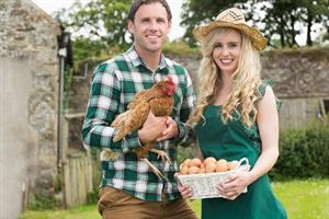 a man holding chicken and a woman holding a basket of eggs