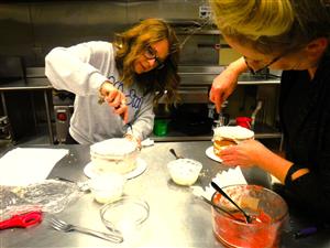 women frosting layered cakes