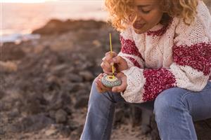 woman painting mandala onto a rock